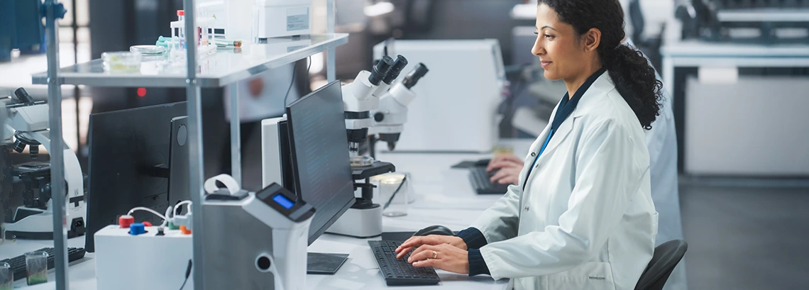 woman with lab coat in a lab looking at computer screen